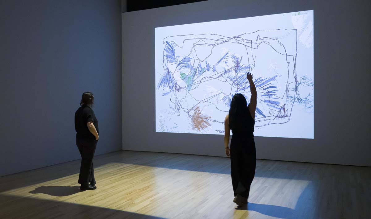 Installation view of Run the Code with viewers interacting with a projection