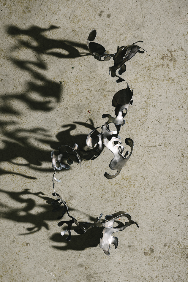 Sculpted metal casts shadows across a wall.