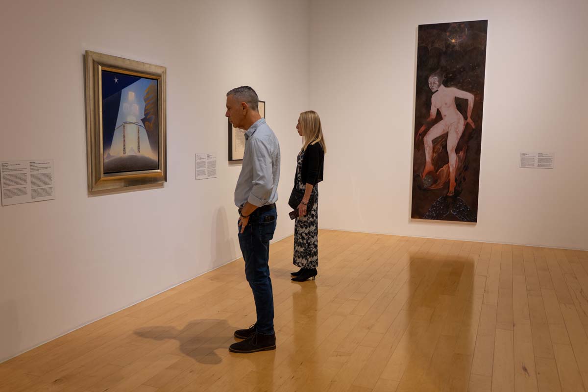 Installation view with an audience member looking at an Agnes Pelton painting.