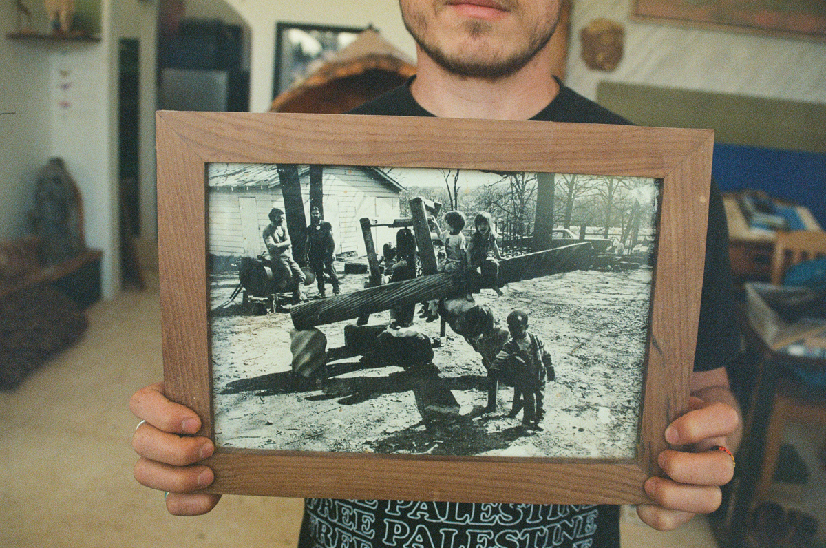 Raini Pachak holds a black-and-white photo of Utah artist Joe Pachak's first playground structure in Arkansas.