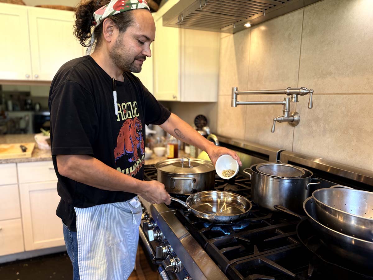 Diné writer and chef Brendan Basham cooking over a stovetop. Basham was selected as the inaugural culinary resident for Ucross's culinary residency in Wyoming.
