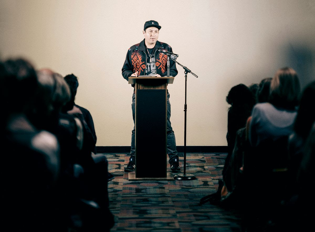 Photo of novelist and IAIA alum Tommy Orange reading on the IAIA campus. Orange was selected as one of the recipients of the 2025 MacArthur genius grant, a top headline for Southwest Art News November 2025.